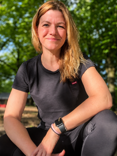Personal Trainerin Marina lächerlt in die Kamera, mit Gewichten in der Hand